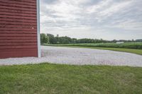 a barn and gravel path on the farm with trees in the background on a cloudy day