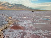 a vast, barren desert area with various colorful structures and water features, with mountains in the distance