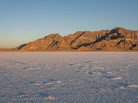 a barren field with snow and mountains in the background, with no people in the shot