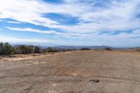 a wide view of a barren field with a dirt road in the foreground, and mountains to the side