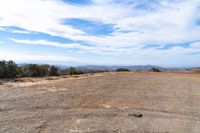 a wide view of a barren field with a dirt road in the foreground, and mountains to the side