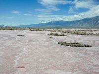 the landscape is almost completely barren and looks like pink sand, so there are some white clouds