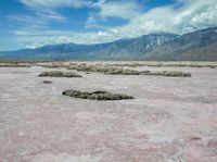 the landscape is almost completely barren and looks like pink sand, so there are some white clouds