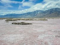 the landscape is almost completely barren and looks like pink sand, so there are some white clouds