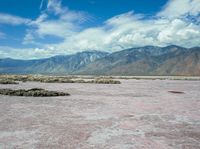 the landscape is almost completely barren and looks like pink sand, so there are some white clouds