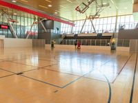 a gymnasium that is equipped with an exercise floor and large windows behind it are basketball hoops