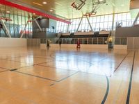 a gymnasium that is equipped with an exercise floor and large windows behind it are basketball hoops