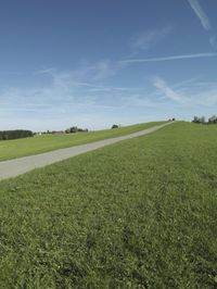 a man in a green field and a person on a red bike are riding along a dirt road