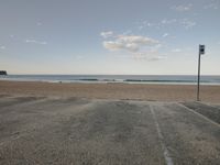 a beach near a car park with an empty parking lot and some waves crashing on the ocean