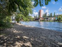 the beach in front of the city building has water and sand around it, with trees and grass