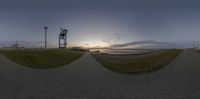 a fish eye view of a beach at dusk with the sun going down in the distance