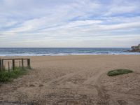 a sandy beach with a gate near the water and some waves on the beach is shown