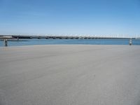 a sandy beach with an overpass that extends from the ocean onto the water in front of it