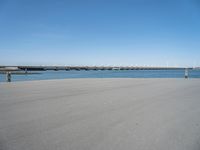 a sandy beach with an overpass that extends from the ocean onto the water in front of it