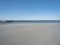 a sandy beach with an overpass that extends from the ocean onto the water in front of it