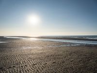 a sunny day on the beach with footprints of people walking on the shore path and footprints left in the sand