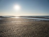 a sunny day on the beach with footprints of people walking on the shore path and footprints left in the sand