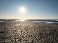 a sunny day on the beach with footprints of people walking on the shore path and footprints left in the sand