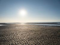 a sunny day on the beach with footprints of people walking on the shore path and footprints left in the sand