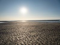 a sunny day on the beach with footprints of people walking on the shore path and footprints left in the sand