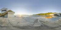 the fisheye lens is taken on the beach house with a boat nearby and a blue sky