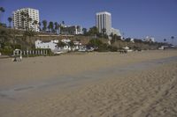 a group of people on a beach next to the ocean and a resort on the horizon