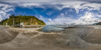 this circular fish eye view captures the boats in the water on a beach near mountains