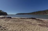 a beach that is sitting in the sand near water and hills of vegetation along the shore