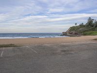 a parking lot is empty on the beach near a ocean bank and grassy shoreline