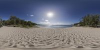 beach is covered by sand under a bright blue sky, as seen through a fisheye lens