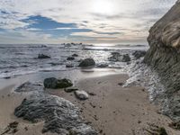 the beach with some rocky shoreline and blue sky over it and water running over it