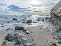 the beach with some rocky shoreline and blue sky over it and water running over it