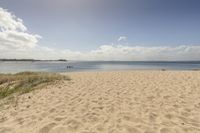 the view from a beach, looking out to sea and grass on either side of the beach