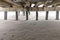 sand under the ground is covering the underneath of a beach structure with pipes and poles