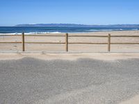 a paved beach with a fence in front of it and the ocean in the distance