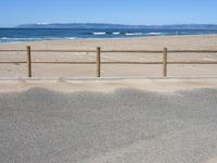 a paved beach with a fence in front of it and the ocean in the distance