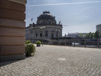 a beautiful building in a city near water with some statues on the wall and a bench nearby