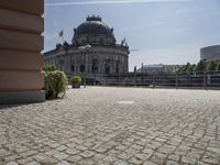 a beautiful building in a city near water with some statues on the wall and a bench nearby