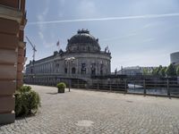 a beautiful building in a city near water with some statues on the wall and a bench nearby