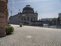 a beautiful building in a city near water with some statues on the wall and a bench nearby