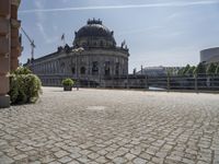 a beautiful building in a city near water with some statues on the wall and a bench nearby