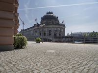 a beautiful building in a city near water with some statues on the wall and a bench nearby