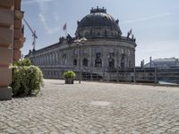 a beautiful building in a city near water with some statues on the wall and a bench nearby