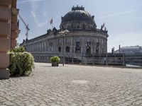 a beautiful building in a city near water with some statues on the wall and a bench nearby