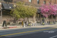 the sidewalk and parking is covered with a lot of trees and flowers in the middle of a city street