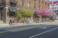 the sidewalk and parking is covered with a lot of trees and flowers in the middle of a city street