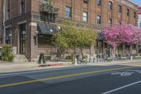 the sidewalk and parking is covered with a lot of trees and flowers in the middle of a city street