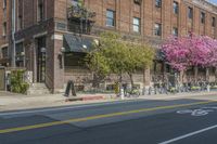 the sidewalk and parking is covered with a lot of trees and flowers in the middle of a city street