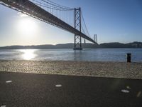 sun shines near the water and bridge over the water on a sunny day, with a sand beach next to it