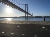 sun shines near the water and bridge over the water on a sunny day, with a sand beach next to it